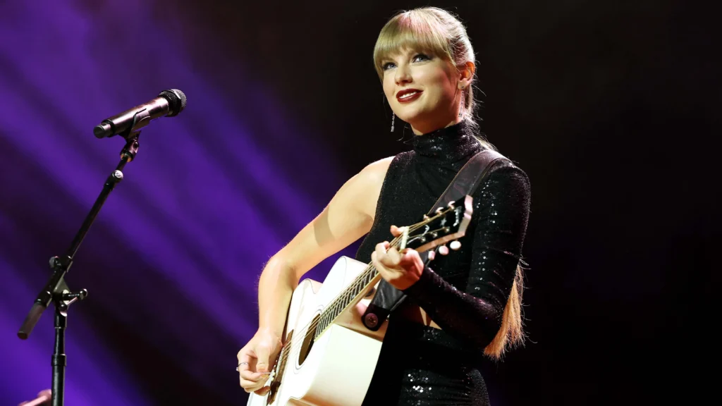 A photo of Taylor Swift performing on stage with lights shining down on her.