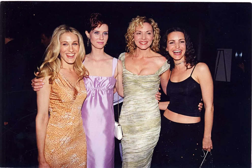 A picture of the three main characters, Carrie, Miranda, and Charlotte, standing together, looking fashionable and chic. The alt text could be "Carrie, Miranda, and Charlotte in 'And Just Like That...'".