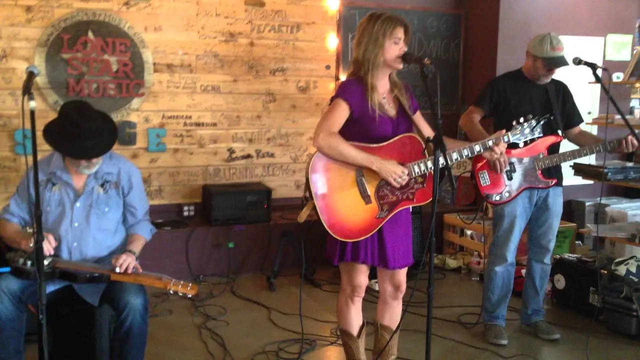 Robyn Ludwick performing on stage with a guitar